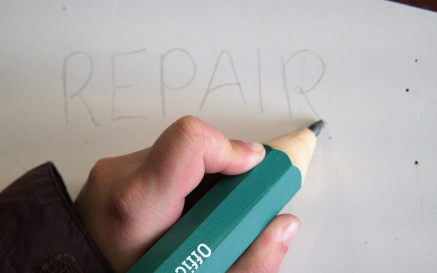 Beitragsbild. Eine Hand zeichnet mit einem großen Bleistift das Wort Repair.